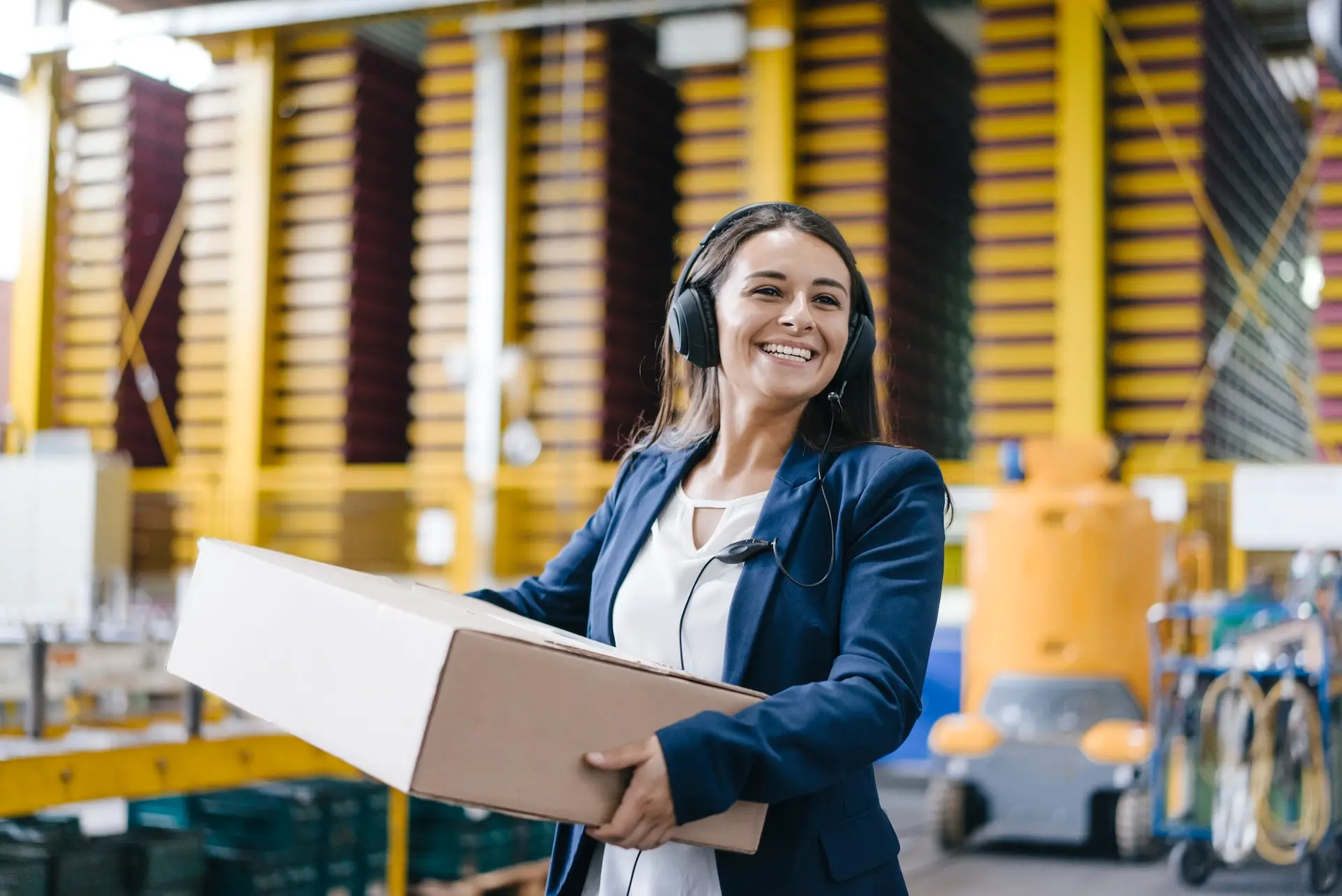 Young woman working at parcel service, carrying parcel in warehouse